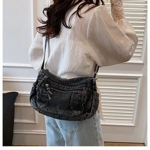 Détail du sac bandoulière croissant en denim noir délavé avec poches zippées multiples