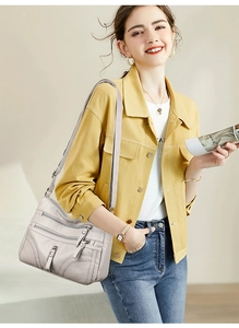 Detail of grey multi-zippered soft leather crossbody bag worn with yellow jacket