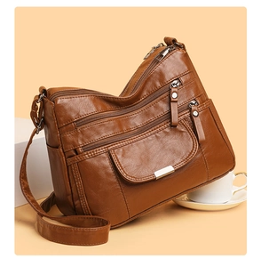 Detail view of brown faux leather shoulder bag with multiple functional silver zippers