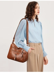 Brown soft PU leather crossbody bag with multiple zippers shown on a model