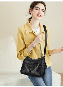 Detailed view of women's black multi-zipper crossbody bag worn by a model in casual style
