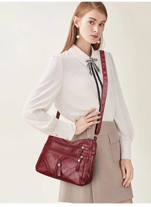 Close-up of wine red faux leather crossbody bag featuring multiple functional zippers