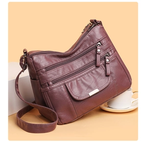 Detail view of purple soft leather crossbody bag with multiple functional zip pockets