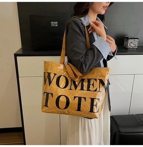 Detail view of large brown tote bag with Women Tote print worn by a model