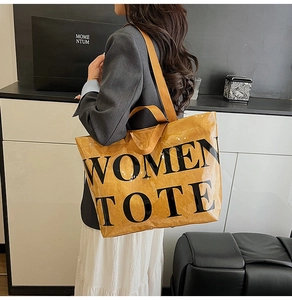 Detailed view of the large glossy brown tote bag with bold black Women Tote lettering