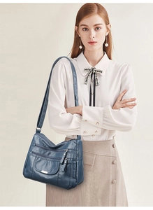 Detail of dark blue soft leather crossbody bag with multiple zippers on model