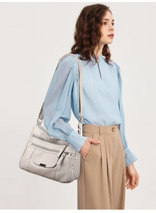 Detailed view of grey soft leather crossbody bag with multiple zippers worn by a model