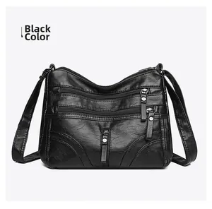 Close-up of black leather crossbody bag with multiple zippers and silver hardware detail