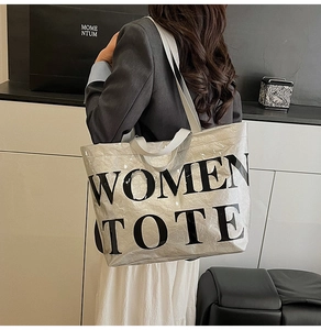 Detailed view of silver metallic tote bag featuring bold black WOMEN TOTE lettering