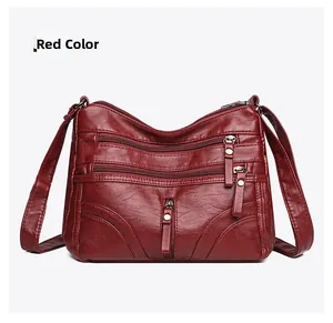 Detail view of red soft leather crossbody bag with multiple zipper pockets and silver hardware
