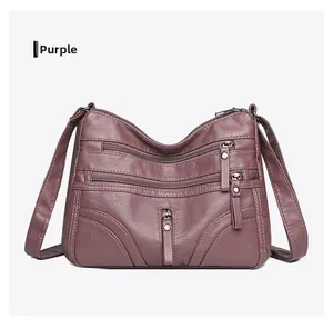 Detail view of purple faux leather crossbody bag with multiple front zipper pockets