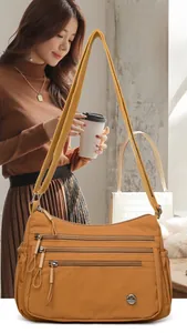 Detail view of caramel nylon shoulder bag featuring multiple zipper compartments and metal logo