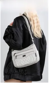 Close-up of a grey quilted crossbody bag featuring multiple zipper pockets and sleek design
