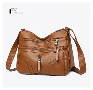 Detail view of deep brown soft leather crossbody bag with multiple front zipper pockets