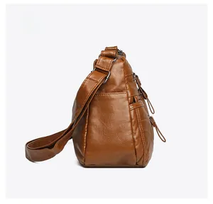Side view of soft dark brown leather crossbody bag with multiple metal zipper pockets
