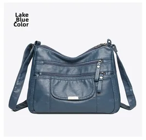 Detail view of lake blue soft leather crossbody bag with multiple zipper compartments