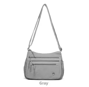 Close-up of grey multi-pocket nylon crossbody bag with smooth zippers and side pocket