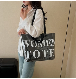 Detail of glossy black tote bag with white WOMEN TOTE print and nylon handles