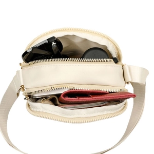 Mini nylon crossbody bag with dual zipper compartments showing internal storage capacity