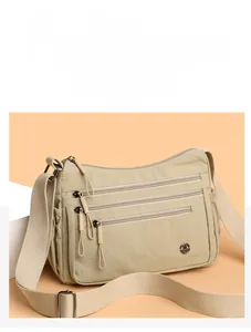Detailed macro view of beige nylon crossbody bag featuring multi-zipper pockets and metal logo