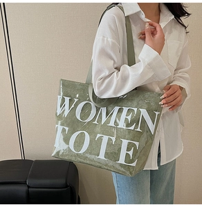 Detail of green minimalist tote bag showing the WOMEN TOTE print and nylon handles