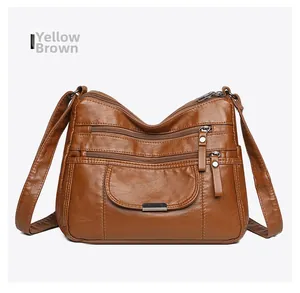 Detailed front view of yellow-brown leather crossbody bag with multiple zipper pockets