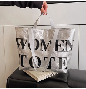 Close-up of silver tote bag with metallic crinkle texture and large Women Tote text