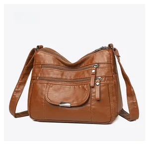 Detailed side view of brown faux leather shoulder bag featuring triple zipper compartments