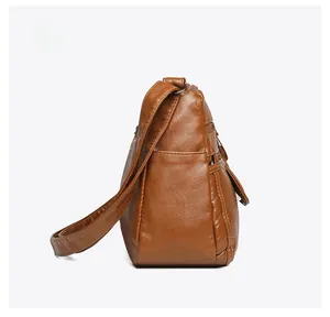 Side view detail of multi-layer brown leather shoulder bag with side pocket and zippers