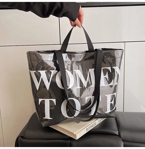 Detail of a black glossy tote bag featuring white WOMEN TOTE text and nylon handles