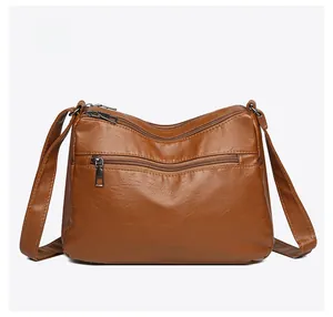 Detailed back view of brown multi-zippered crossbody bag with soft leather texture