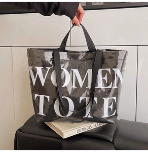 Detail of glossy black large tote bag with white WOMEN TOTE text on white books