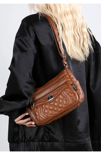 Detail of brown quilted leather crossbody bag with multiple zippers and adjustable strap