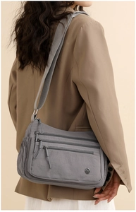 Close-up of grey crossbody bag with multiple zip pockets and a wide fabric strap