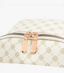 Dettaglio delle cerniere in oro rosa liscio sullo zaino beige con motivo a trifoglio