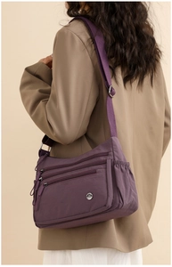 Detail of purple nylon crossbody bag with multi-zipper pockets and adjustable strap