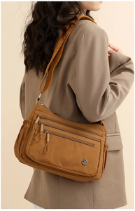 Detail of caramel nylon crossbody bag featuring three zipper pockets and adjustable strap