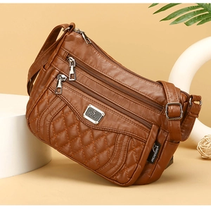 Detailed view of brown quilted crossbody bag with silver zippers and adjustable strap