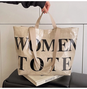 Detail of minimalist beige canvas and PVC tote bag with bold black WOMEN TOTE lettering