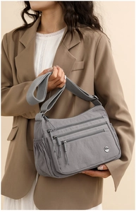 Detail of grey multi-zipper crossbody bag with adjustable strap on a brown blazer outfit