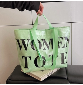 Macro detail of mint green tote bag with woven texture and bold black letters