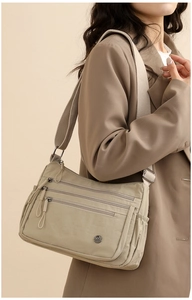 Khaki nylon crossbody bag with multi-pocket design and wide canvas strap worn by model