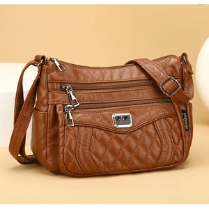 Close-up of brown quilted faux leather shoulder bag featuring multiple zipper pockets