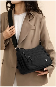 Detail of black multi-pocket crossbody bag with nylon texture and adjustable wide strap