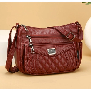 Close-up of wine red quilted crossbody bag with multiple zippers and metallic S sport logo