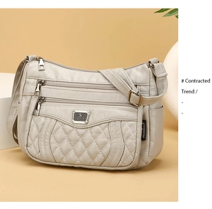 Detail of light grey quilted shoulder bag with multiple zippers and soft leather texture