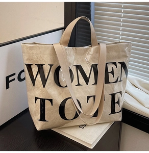 Detail of waterproof beige Tyvek tote bag featuring large black WOMEN TOTE typography print