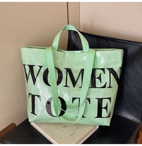 Detailed view of green patent leather tote with WOMEN TOTE print on a black chair