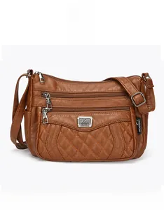 Macro detail of brown quilted leather bag with silver zippers and adjustable strap