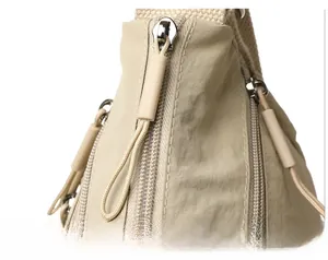 Detailed close-up of high-quality zipper and durable nylon fabric on beige tote bag